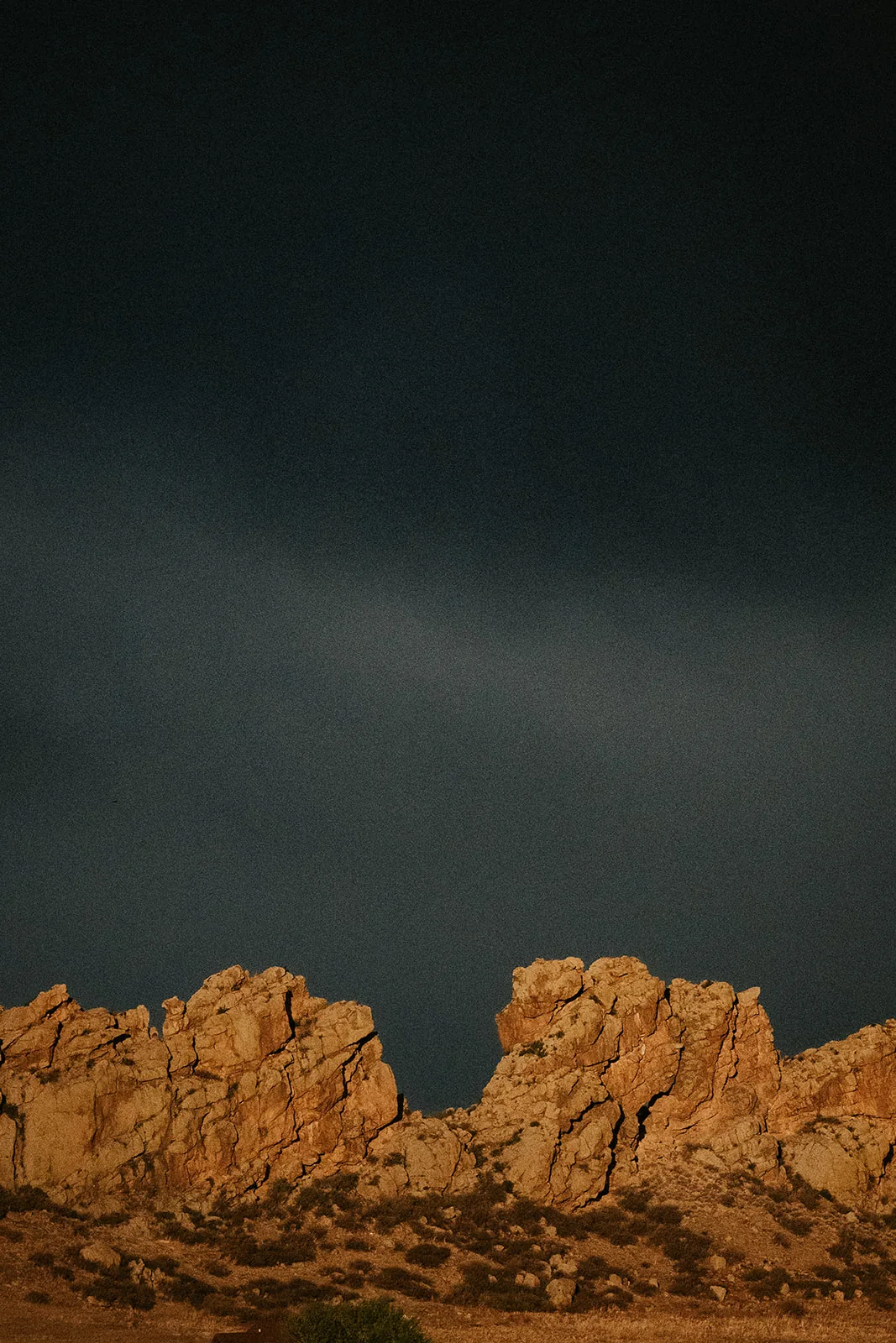 Sunlit sandstone formations of The Devil&rsquo;s Backbone under a dark sky