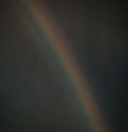 A faint rainbow against a dark sky